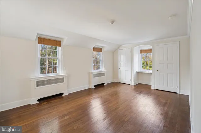 a view of an empty room with window and wooden floor
