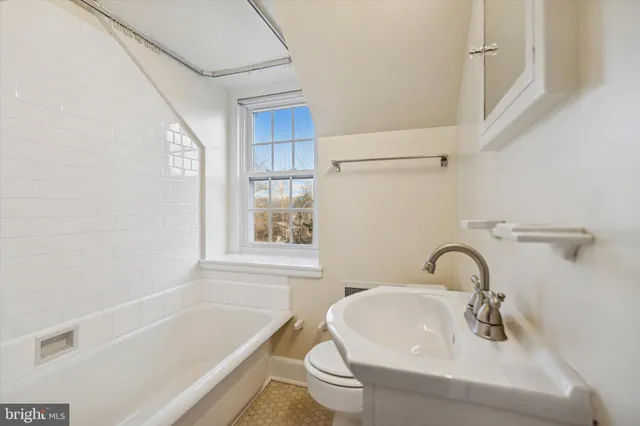 a bathroom with a sink and bathtub with window