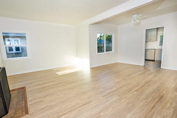 a view of an empty room with wooden floor and a window