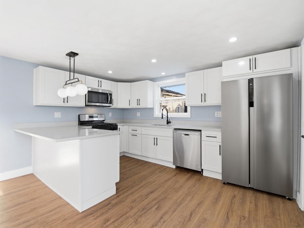 12 Howard Street Lynn, MA 01902 - Photo 5 of 26 a kitchen with stainless steel appliances granite countertop a refrigerator a stove top oven a sink and dishwasher with wooden floor