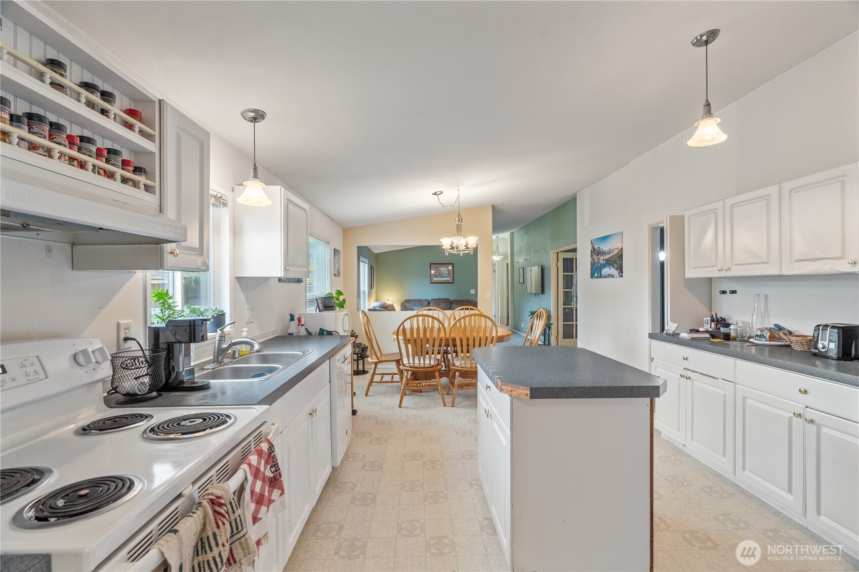 1614 West Martin Street Elma, WA 98541 - Photo 8 of 37 a large kitchen with kitchen island a stove a sink a refrigerator and white cabinets with wooden floor