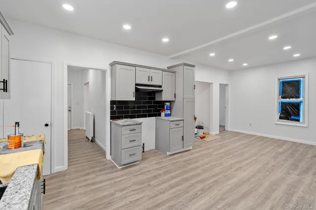 a large white kitchen with stainless steel appliances granite countertop a stove a sink and a refrigerator