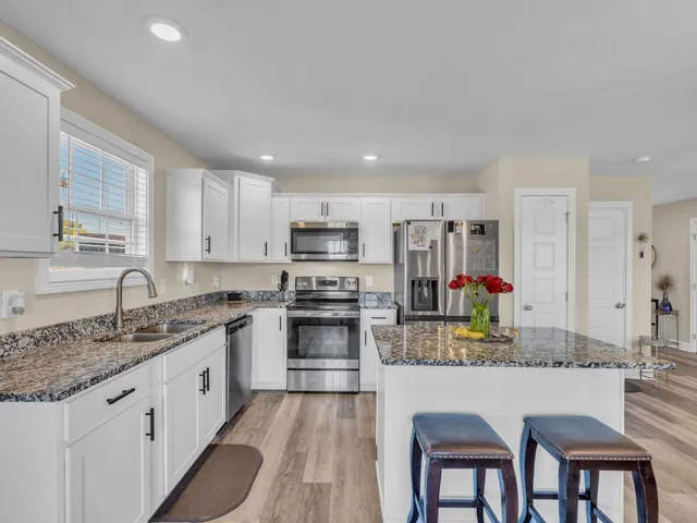 a kitchen with kitchen island granite countertop a sink cabinets stainless steel appliances and a counter space