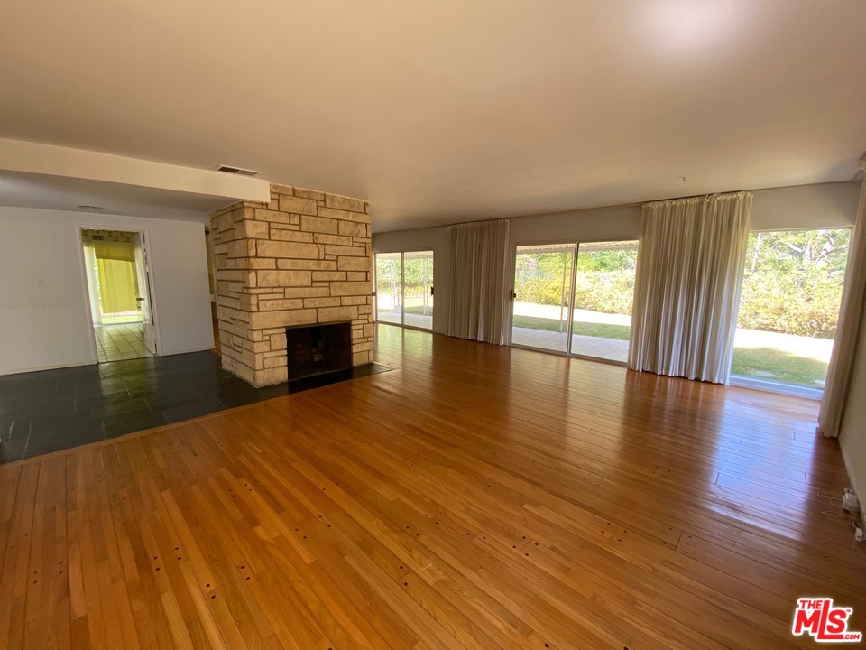 9748 Oak Pass Road Beverly Hills, CA 90210 - Photo 6 of 20 an empty room with wooden floor and fireplace