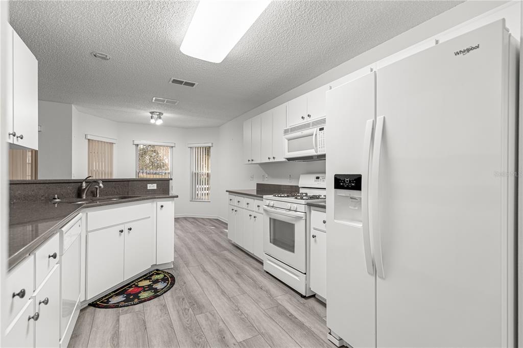 9614 Southwest 93rd Loop Ocala, FL 34481 - Photo 23 of 45 a kitchen with granite countertop white cabinets and white appliances