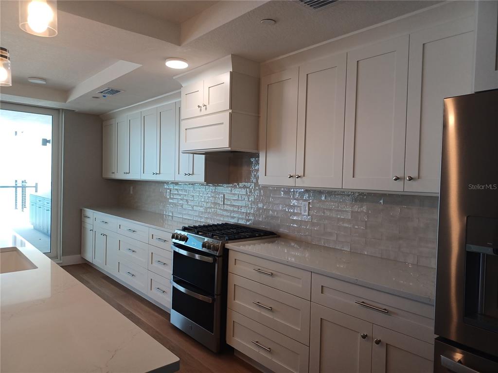 14048 Gulf Boulevard, Unit 402 Madeira Beach, FL 33708 - Photo 4 of 11 a kitchen with granite countertop white cabinets and stainless steel appliances