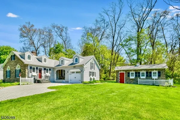 a view of a white house with a big yard and large trees