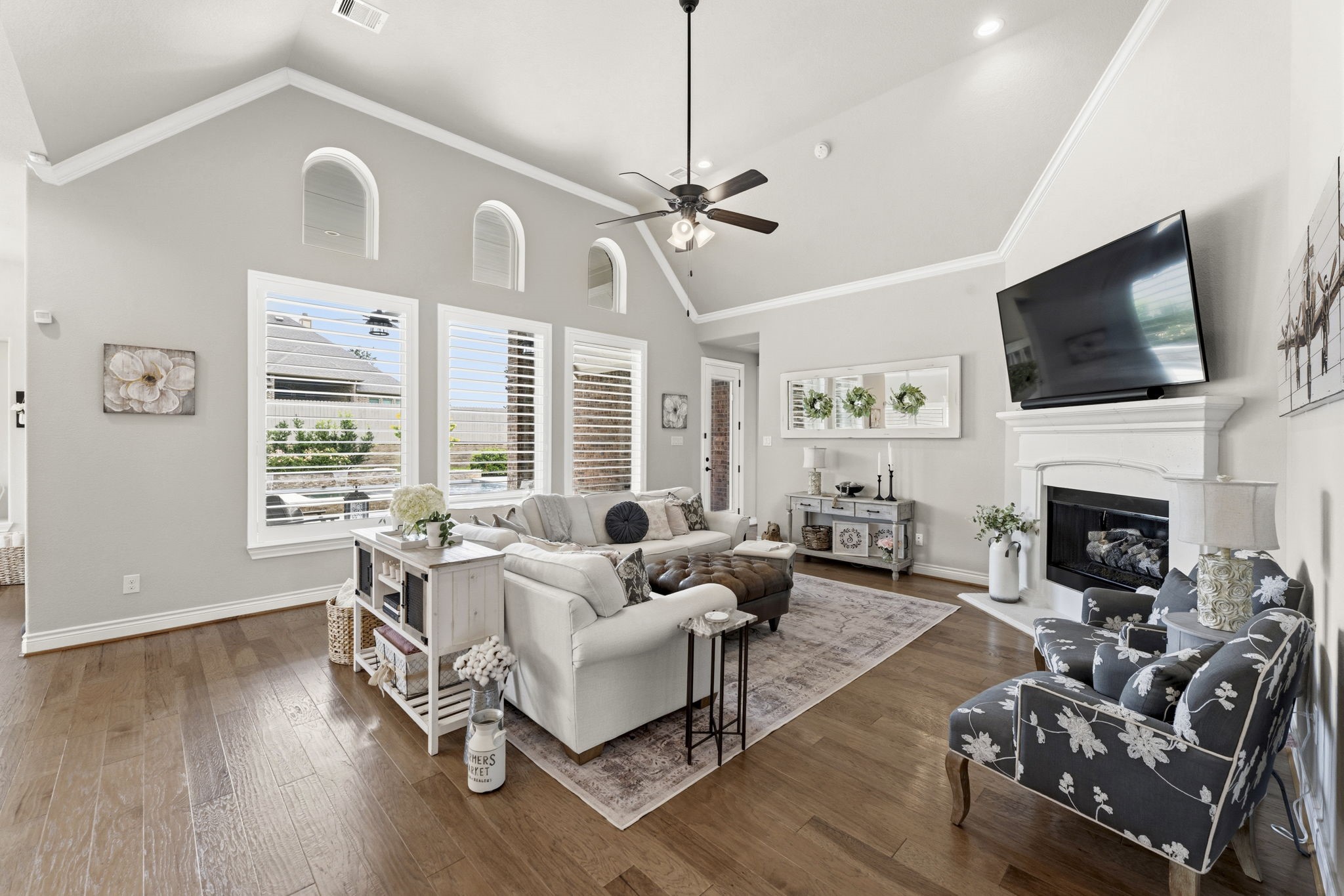 14012 Beartooth Bend Trail Conroe, TX 77384 - Photo 48 of 50 Relax and unwind in this warm and welcoming Family Room, where three large windows with plantation shutters and overhead transoms frame breathtaking views of the spacious backyard, covered porch, and pool/spa. The open floor plan allows for effortless entertaining and everyday living—a true showcase of timeless design and sophisticated style, perfectly suited for family living and hosting guests alike.