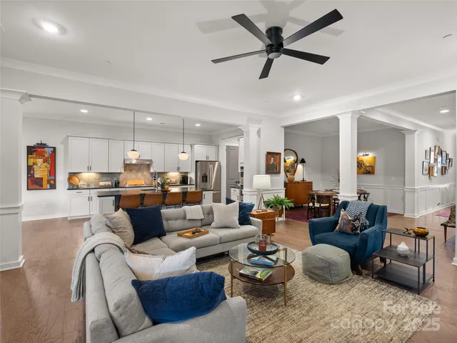 a living room with furniture kitchen view and a chandelier