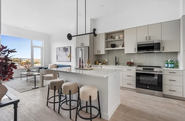 a kitchen with stainless steel appliances granite countertop a stove top oven a sink a dining table and chairs with wooden floor