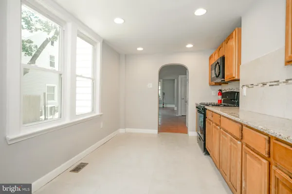 a large kitchen with stainless steel appliances granite countertop a large window
