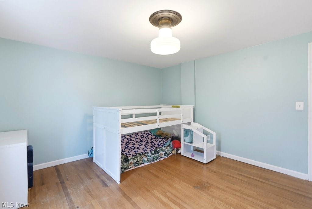 149 North Medina Line Road Akron, OH 44333 - Photo 18 of 42 Hardwood flooring, light blue wall paint, white trim, and a ceiling-mounted light fixture