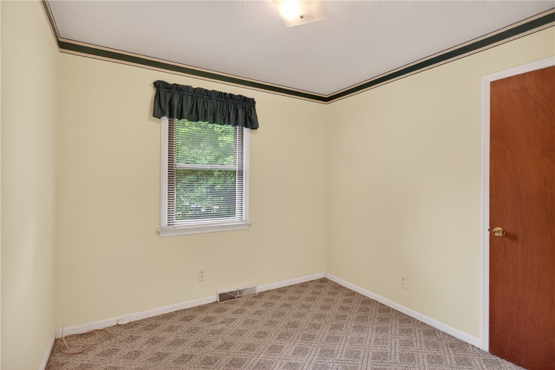 112 Holliday Lane Pendleton, SC 29670 - Photo 29 of 42 Well-lit sleeping quarters with plush, patterned carpet and a view of verdant trees.