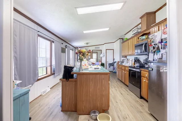 a living room with stainless steel appliances furniture and a kitchen view