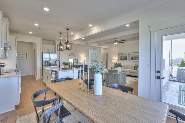 a kitchen with a dining table chairs wooden floor and appliances