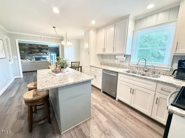 a kitchen with granite countertop sink stove and white cabinets with wooden floor
