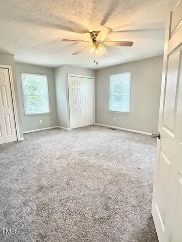 an empty room with windows and fan