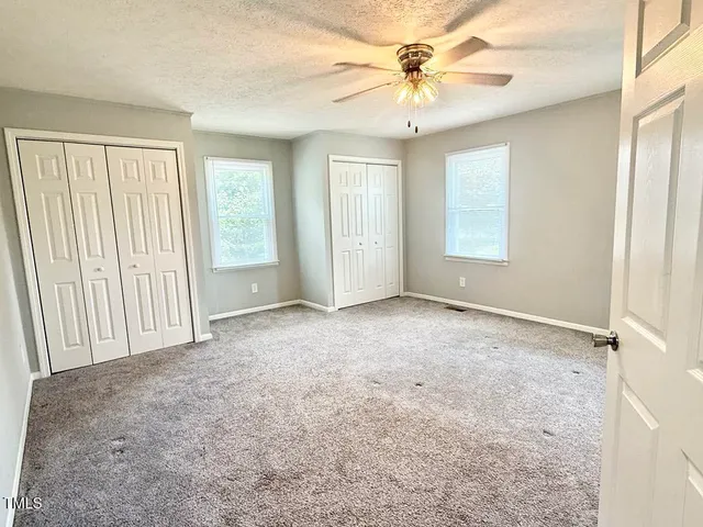an empty room with windows and chandelier fan