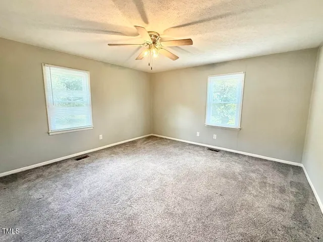 an empty room with windows and fan