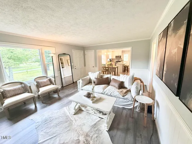 a living room with furniture large window and wooden floor