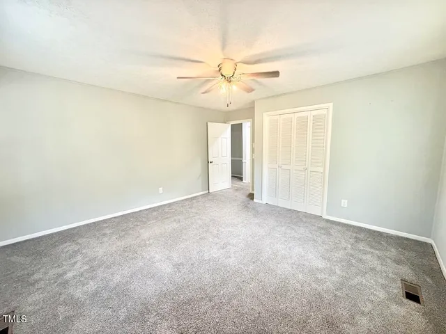 an empty room with windows and fan