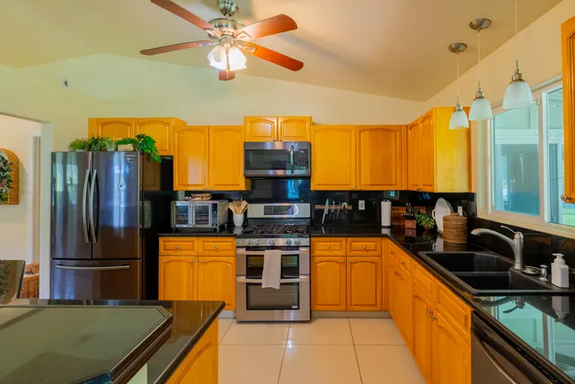 a kitchen with stainless steel appliances granite countertop a sink a stove and a refrigerator