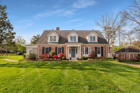 a front view of a house with a big yard and large trees