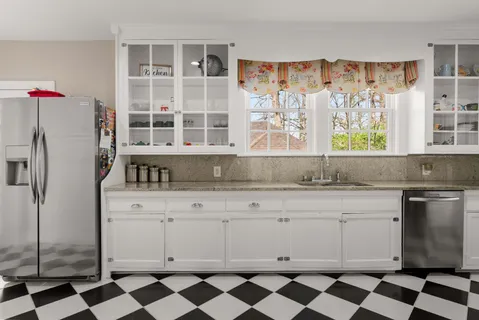 a kitchen with a checkered floor and white cabinets