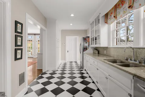 a kitchen with a checkered floor and white cabinets