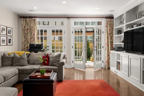 a living room with furniture a flat screen tv and a floor to ceiling window