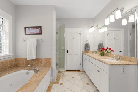 a bathroom with a bathtub a double vanity sink and a large mirror