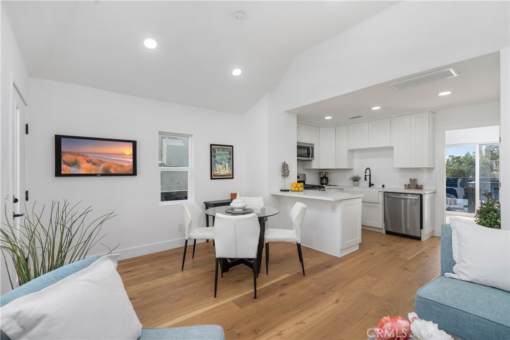 a living room with stainless steel appliances kitchen island granite countertop furniture wooden floor and a kitchen view