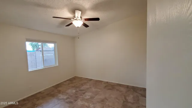 an empty room with windows and fan