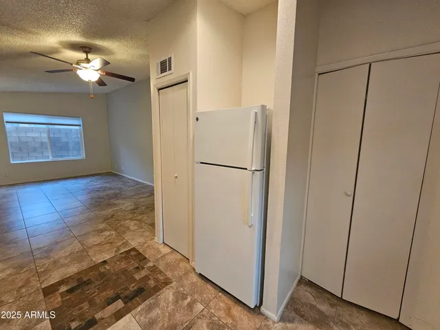 a view of a hallway with a refrigerator and chandelier