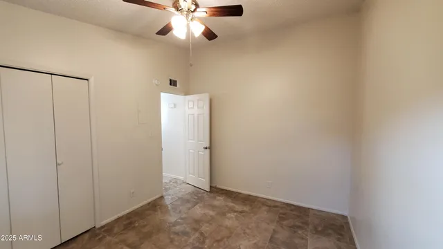 an empty room with a ceiling fan and a window