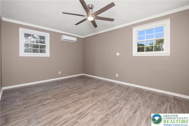 a view of an empty room with window and wooden floor