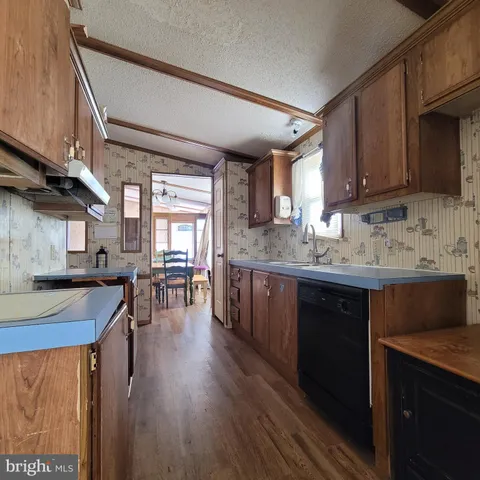 a kitchen with stainless steel appliances granite countertop wooden floors wooden cabinets a sink and a stove