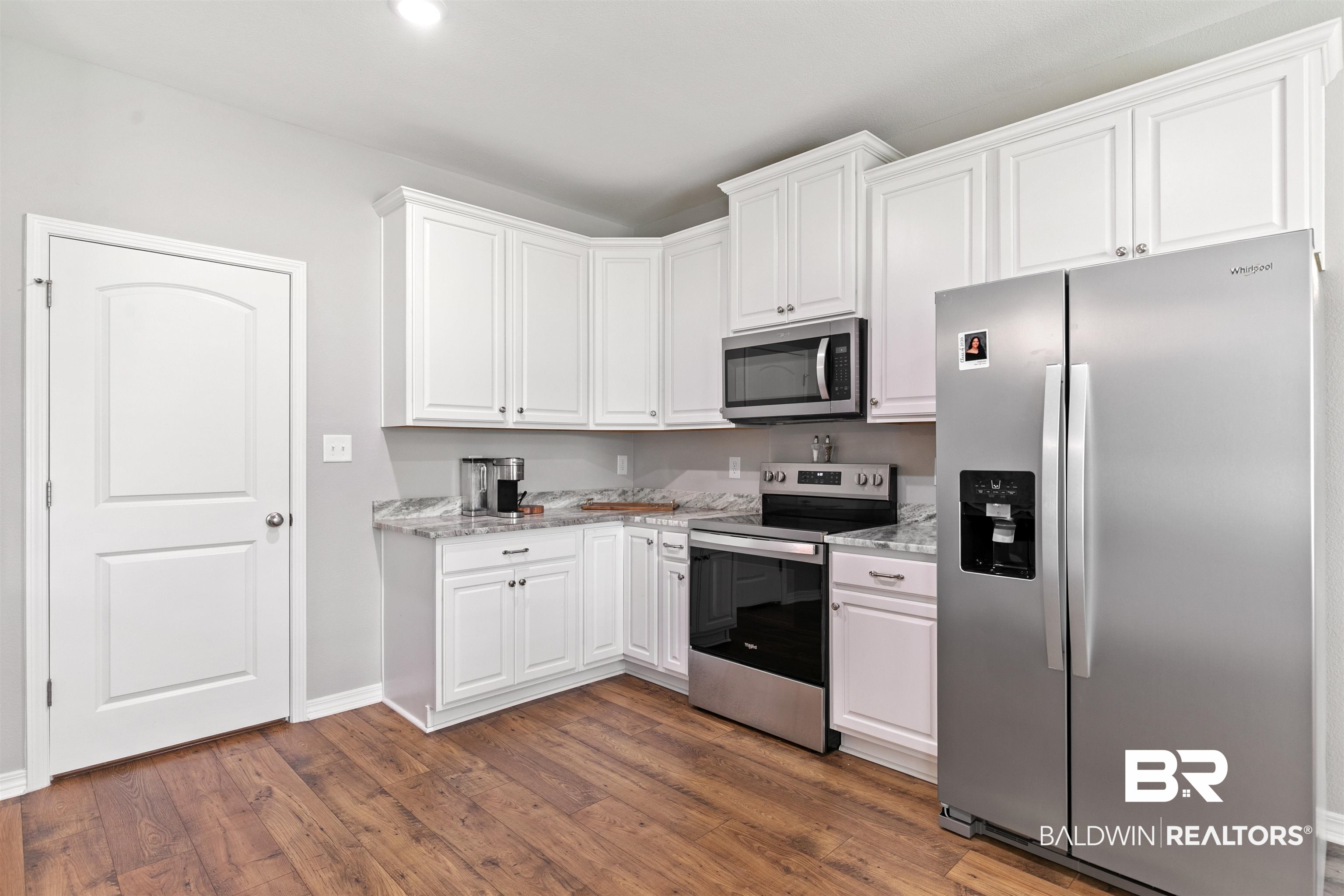 8552 March Road Irvington, AL 36544 - Photo 11 of 28 Modern kitchen featuring white cabinetry, stone-look countertops, and wood-finish flooring