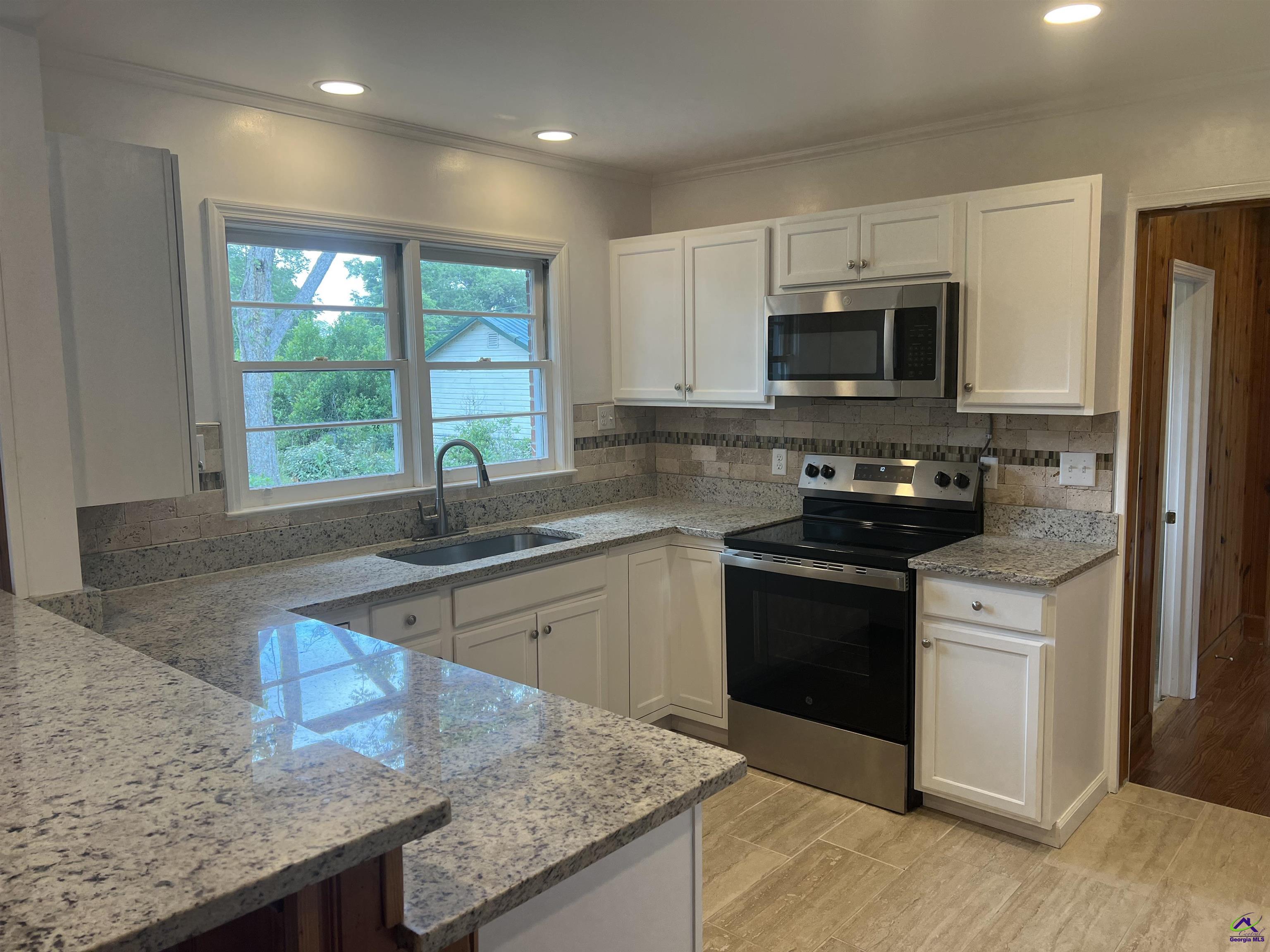 145 South 2nd Street Cochran, GA 31014 - Photo 3 of 24 a kitchen with stainless steel appliances granite countertop a sink a stove a microwave a refrigerator and cabinets
