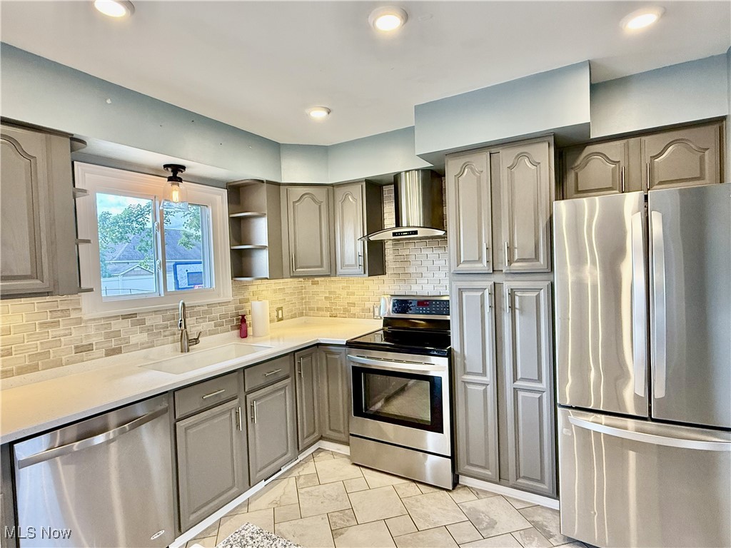 2900 Shellhart Road Barberton, OH 44203 - Photo 2 of 44 Kitchen with stainless steel appliances, backsplash, wall chimney exhaust hood, gray cabinetry, and recessed lighting