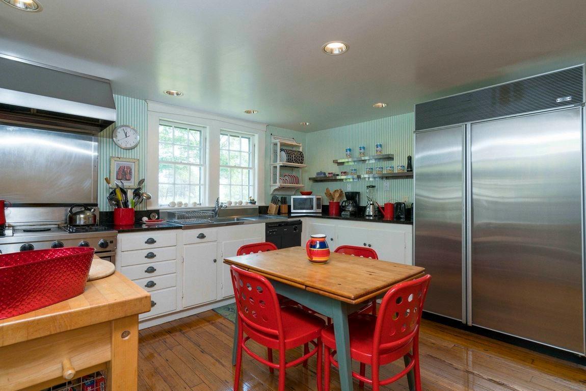 545 Old Harbor Road Chatham, MA 02633 - Photo 29 of 35 a kitchen with a refrigerator a stove and a dining table with wooden floor