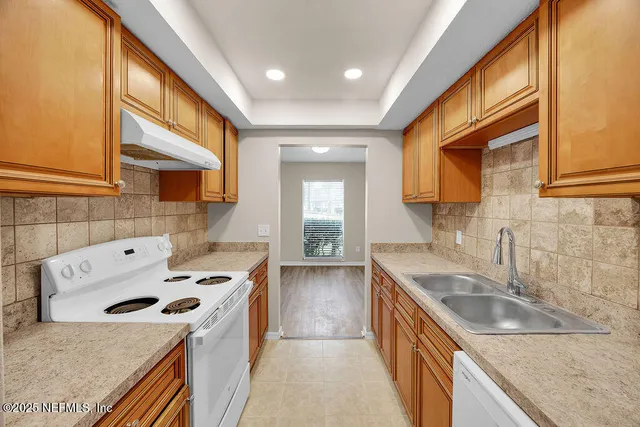 a kitchen that has a sink a stove and wooden floor