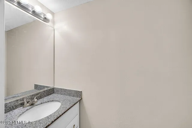 a bathroom with a granite countertop sink and a mirror