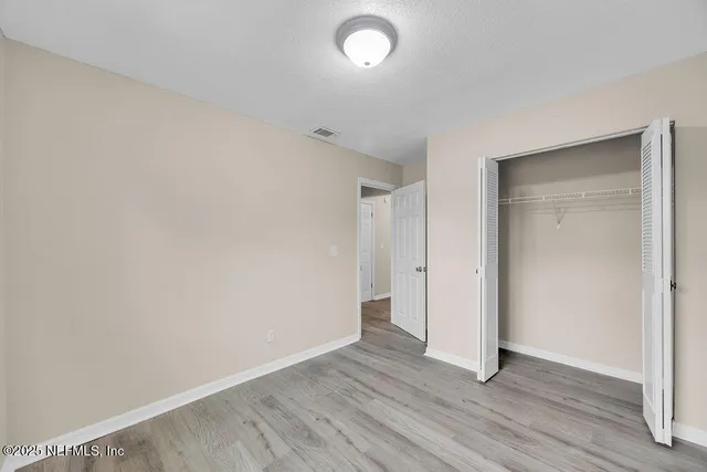a view of an empty room with wooden floor and closet