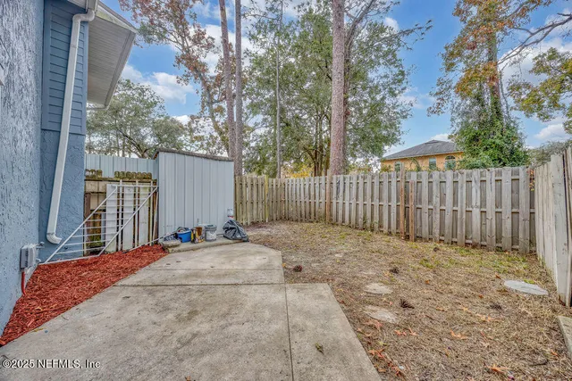 a view of backyard with wooden fence and trees