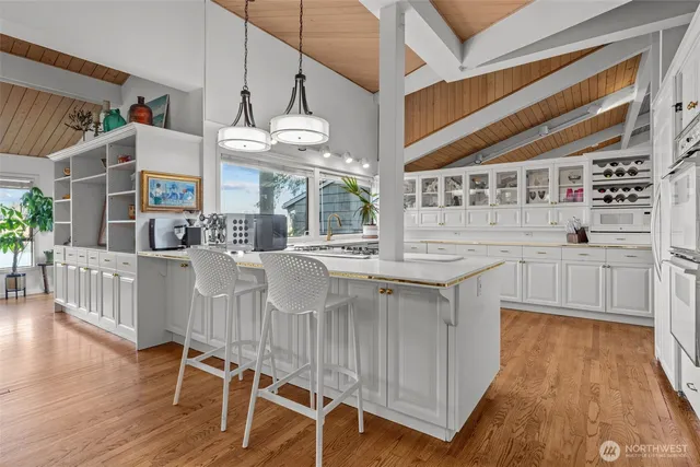 a kitchen with stainless steel appliances kitchen island granite countertop a table chairs in it and wooden floors