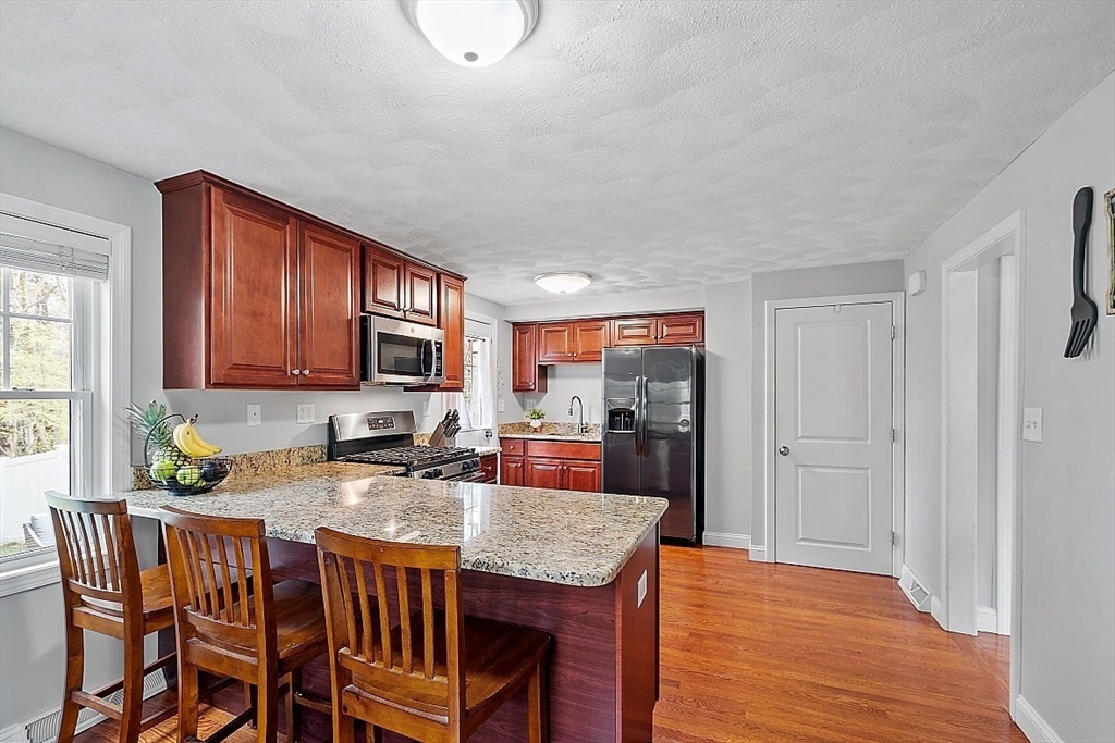 26 Pondover Road, Unit 26 Billerica, MA 01821 - Photo 2 of 23 a kitchen with stainless steel appliances granite countertop a stove a refrigerator a sink a dining table and chairs with wooden floor