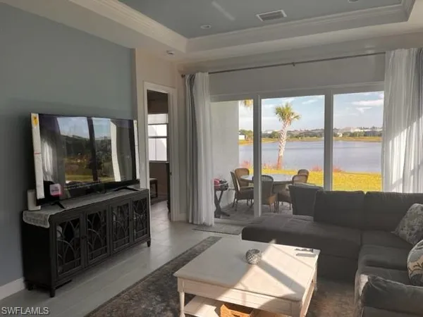 a living room with furniture a flat screen tv and a floor to ceiling window