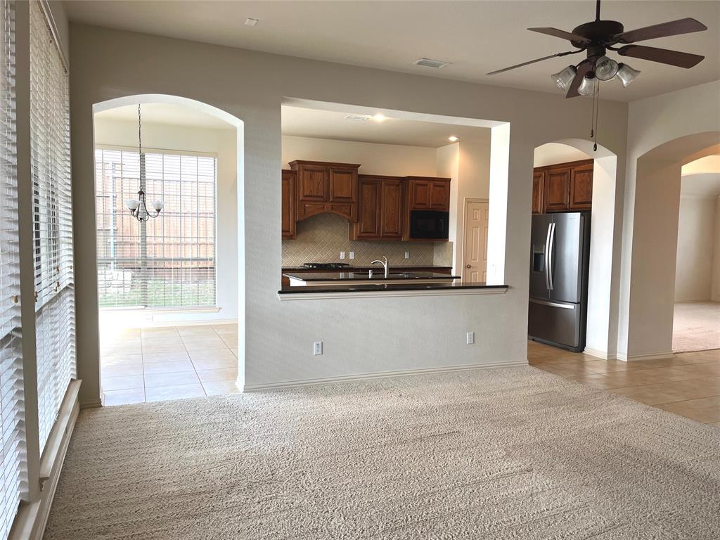 4101 White Porch Road Plano, TX 75024 - Photo 8 of 18 Kitchen featuring wood cabinetry, dark countertops, and a stainless-steel refrigerator, overlooking the family room with a wall of windows.