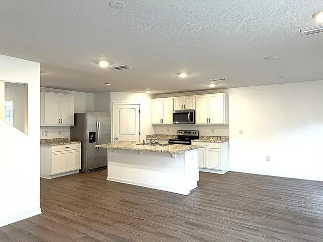 a kitchen with stainless steel appliances a stove top oven a sink a refrigerator a center island and cabinets